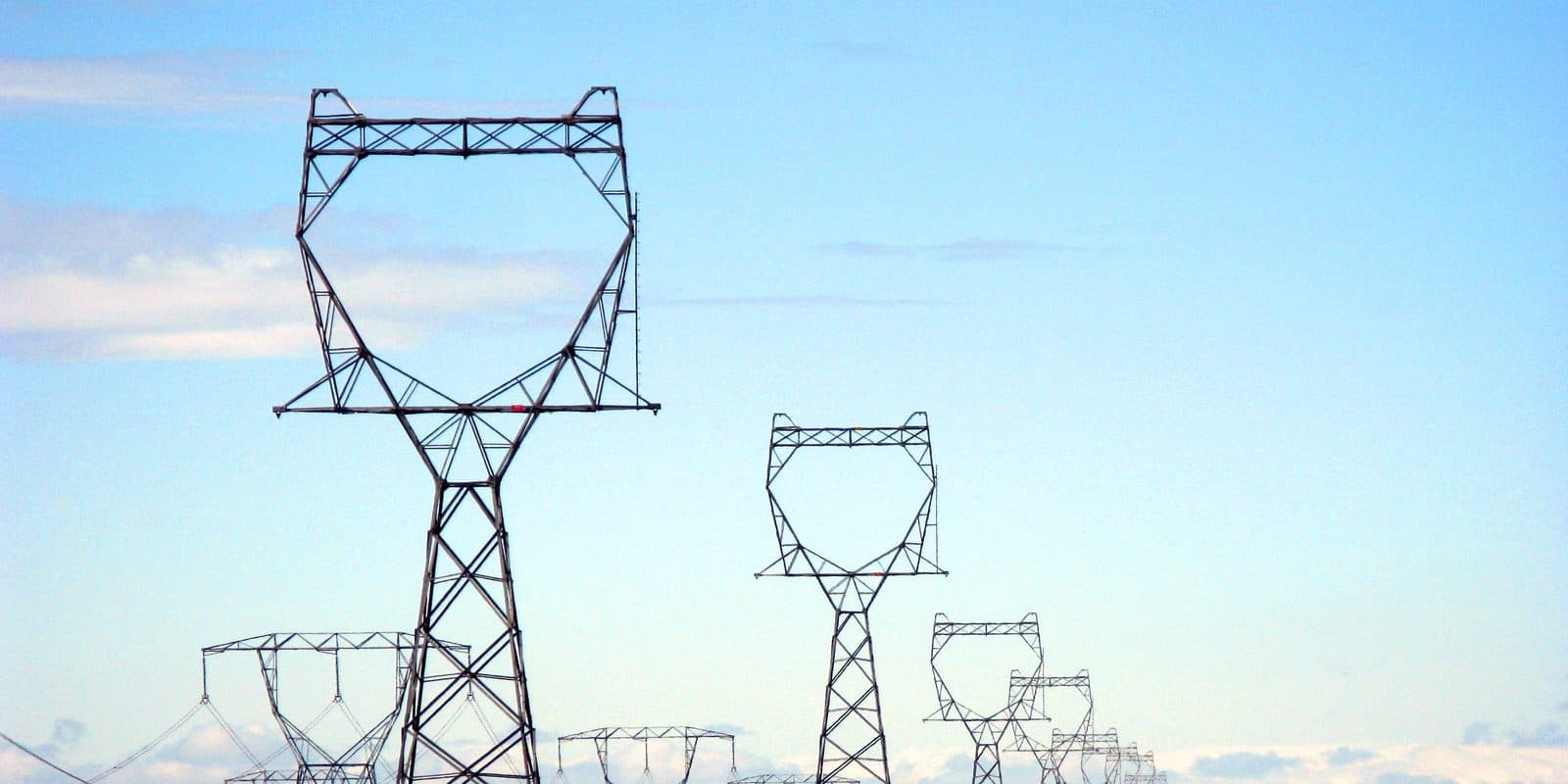 A line of high voltage transmission towers running across open ground.