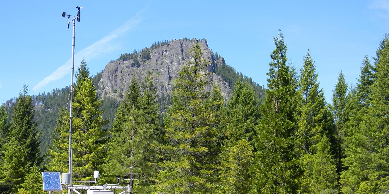 A remote automated weather station recording conditions in a mountain meadow.